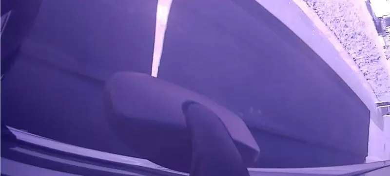 A vehicle camera frame recorded in daylight in which the entire picture carries a violet cast.