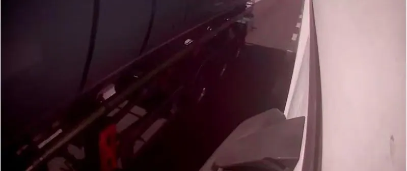 A vehicle camera frame of a scene already in shadow, with a magenta cast across the whole picture.